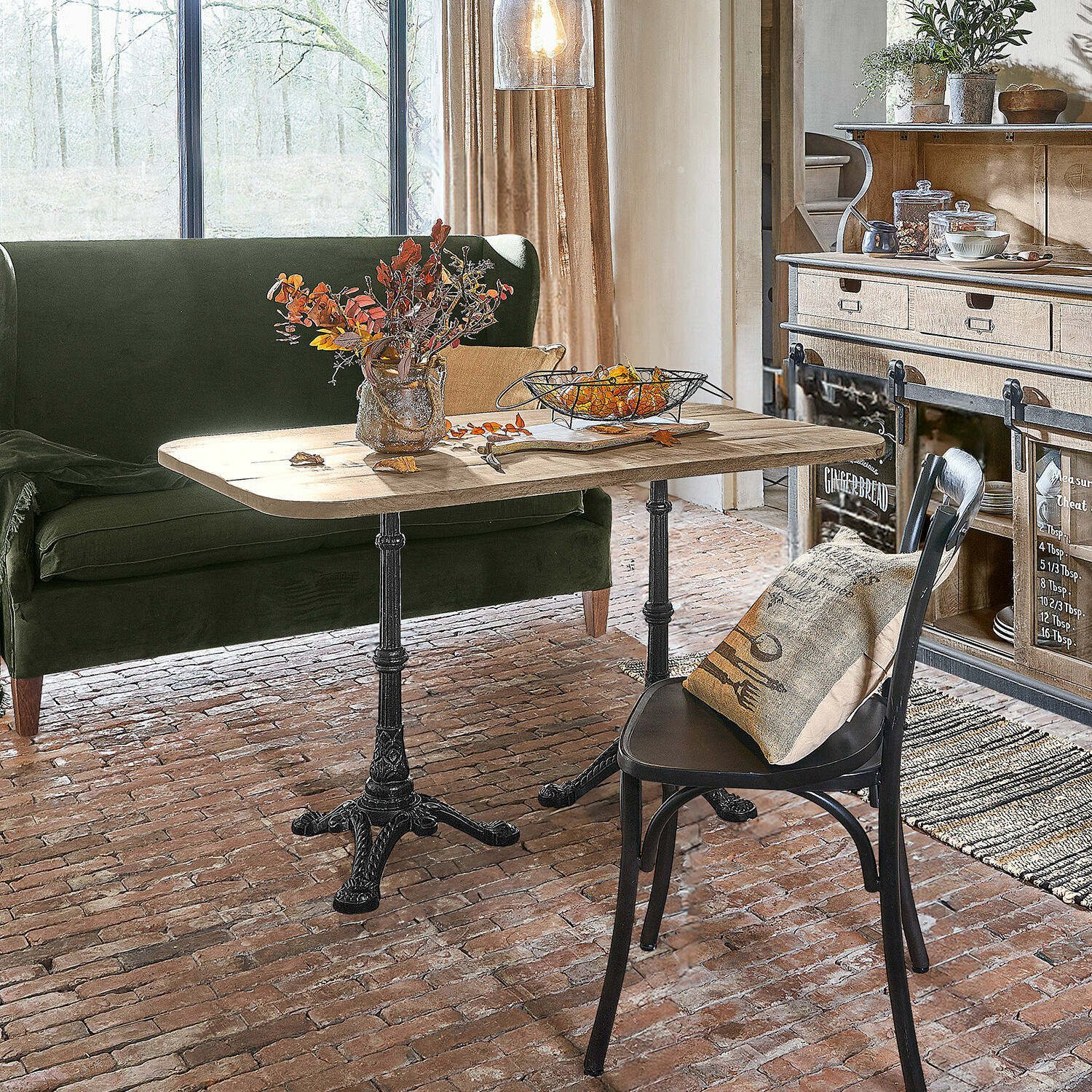 Rustykalny stół z drewnianym blatem i żelaznymi nogami w przytulnym salonie z zieloną sofą