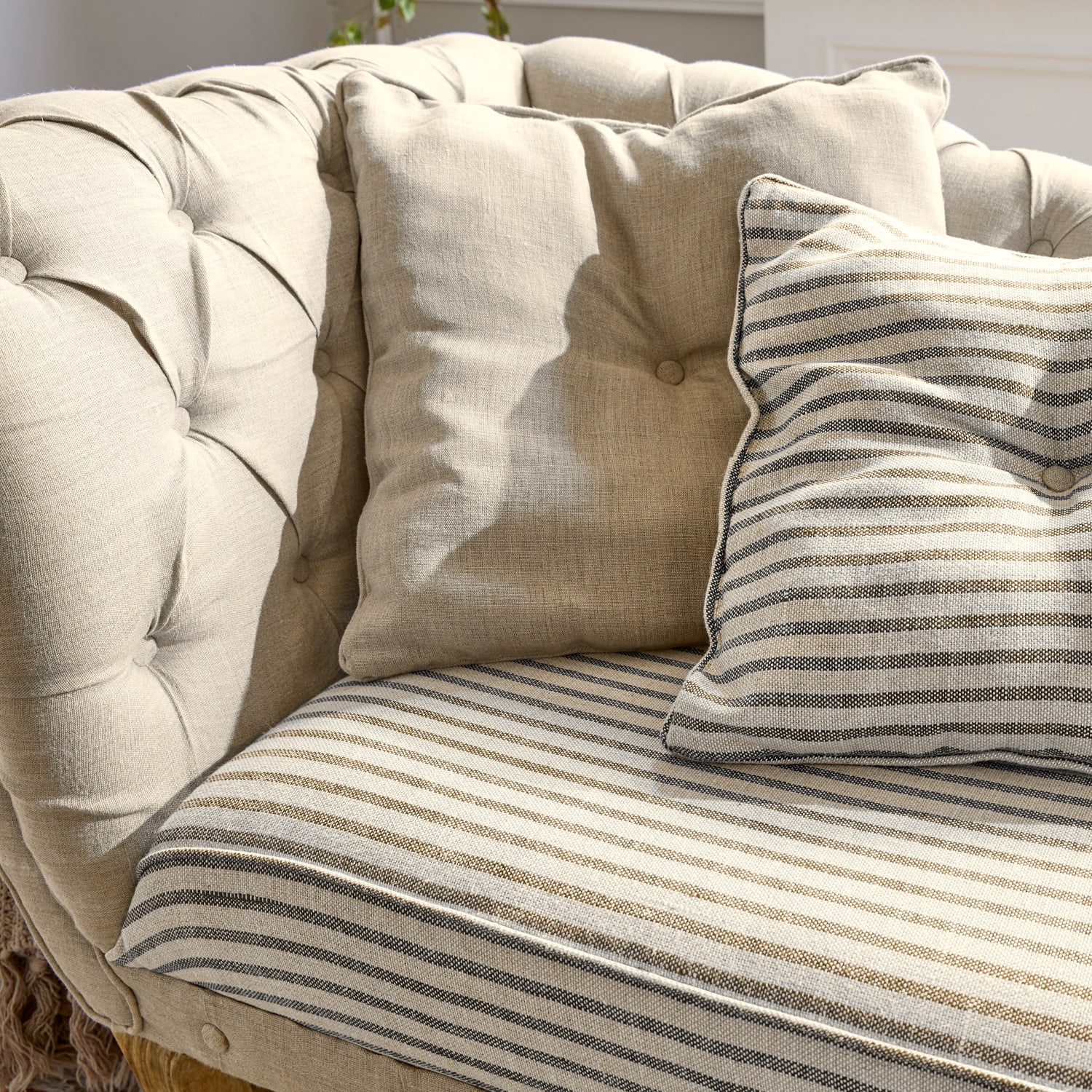 Beżowa tapicerowana sofa z poduszkami w paski i gładkimi, miękka tkanina, mebel wypoczynkowy