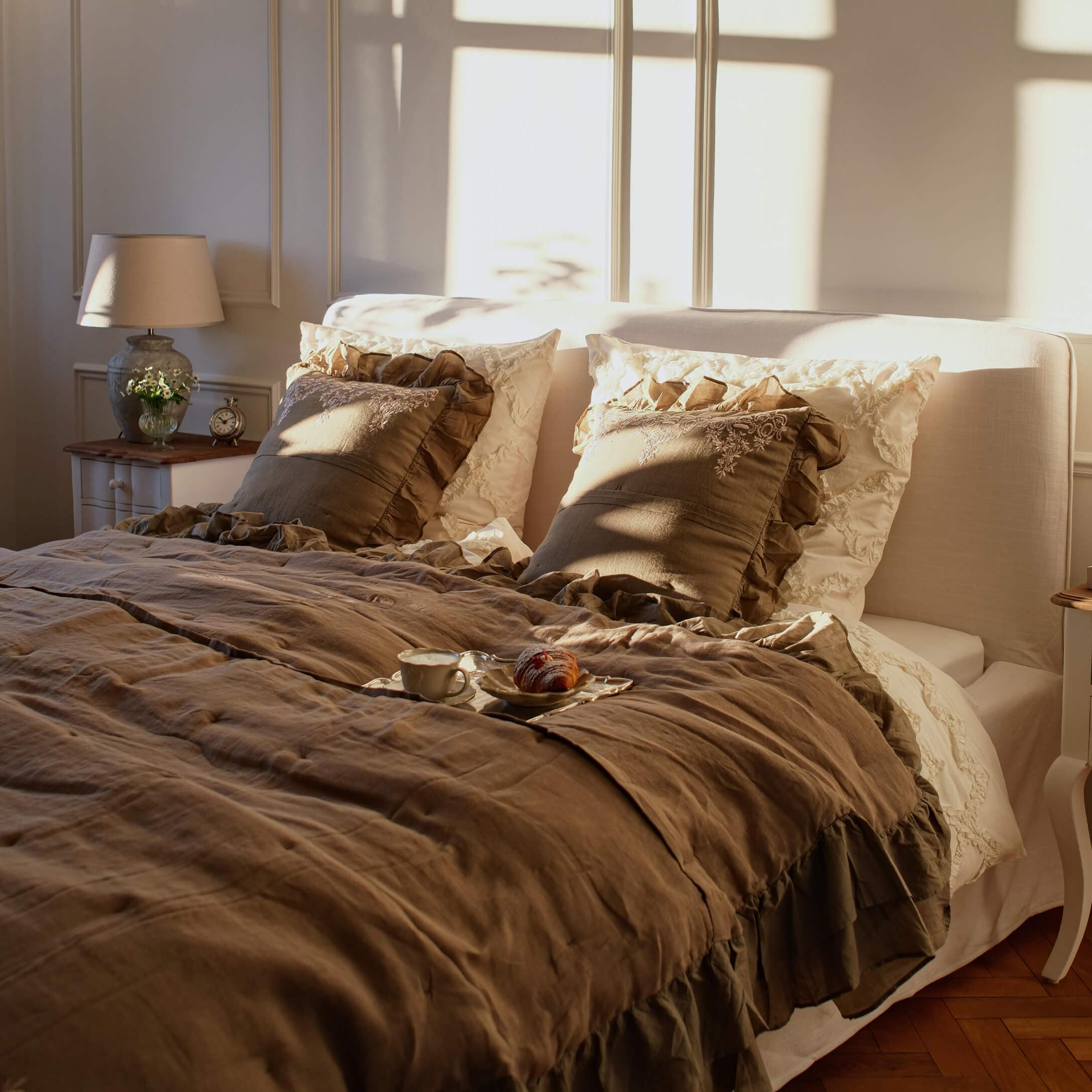 Przytulna sypialnia z beżową pościelą lnianą i poduszkami z falbanami w ciepłych odcieniach brązu