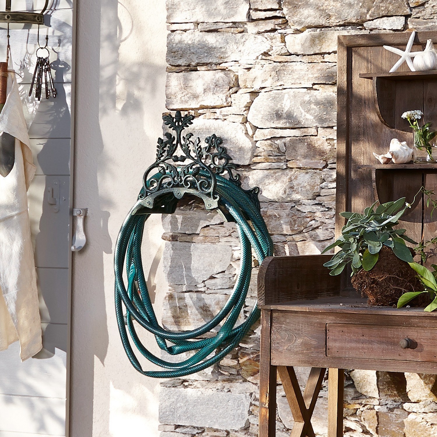 Uchwyt na wąż ogrodowy Mathis Ozdobny metalowy uchwyt na wąż ogrodowy w stylu vintage na kamiennej ścianie