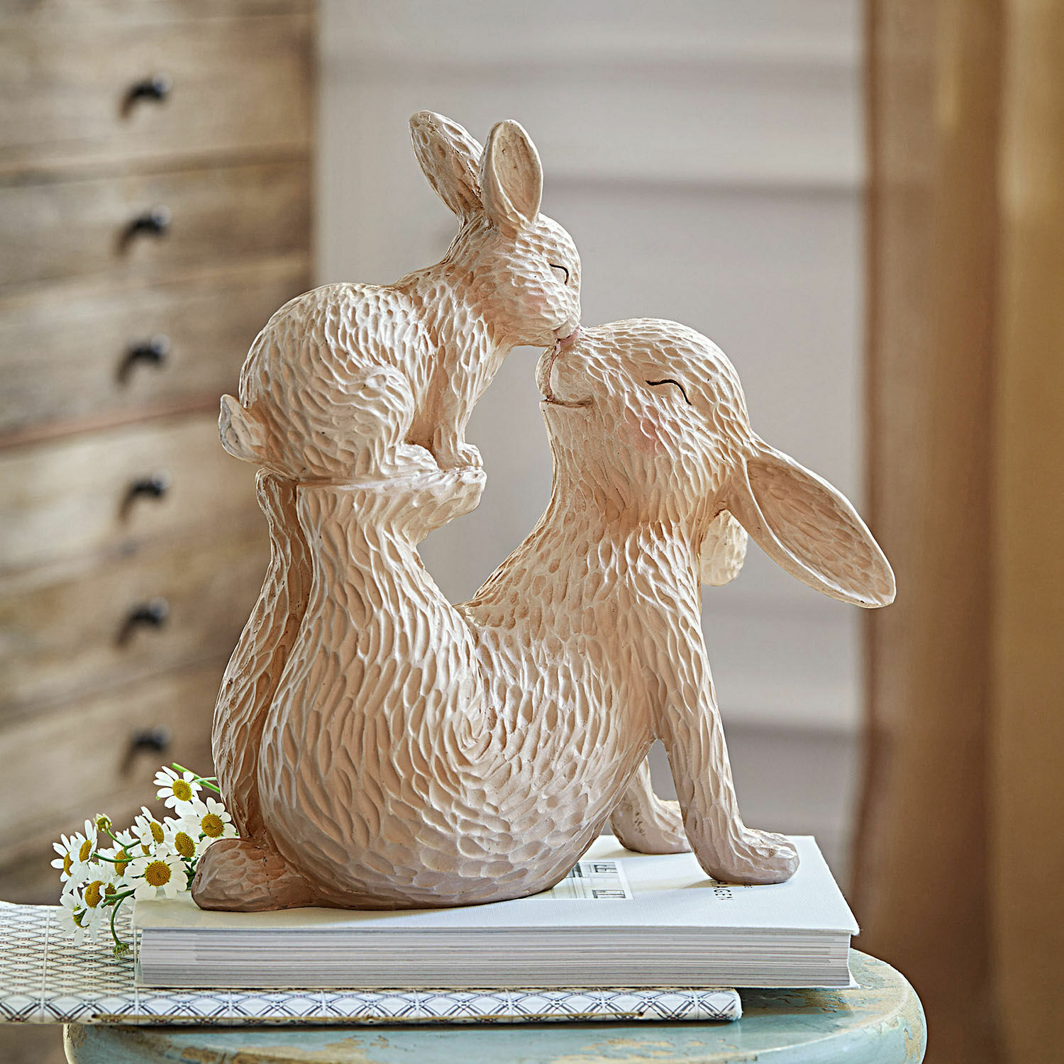 Zajączki dekoracyjne Trista Beżowa ceramiczna figurka dwóch królików w zabawnej pozie na stole z książkami
