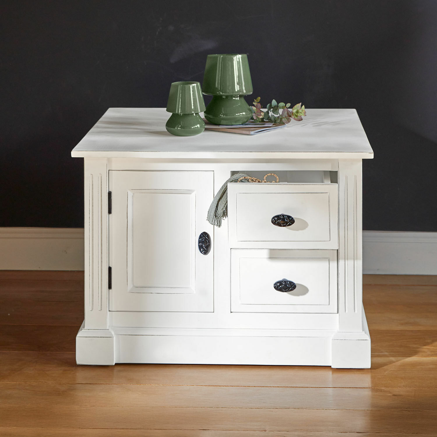 Biały drewniany stolik z szufladami i zielonymi ceramicznymi lampami na blacie, mebel do salonu