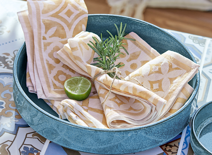 Niebieska ceramiczna misa z beżowo-białymi lnianymi serwetkami i plasterkiem limonki, styl śródziemnomorski