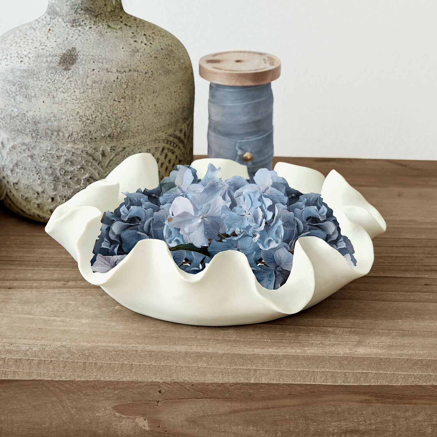 Miska Lunettas Biała ceramiczna miska z falistym brzegiem z niebieskimi kwiatami na drewnianym stole