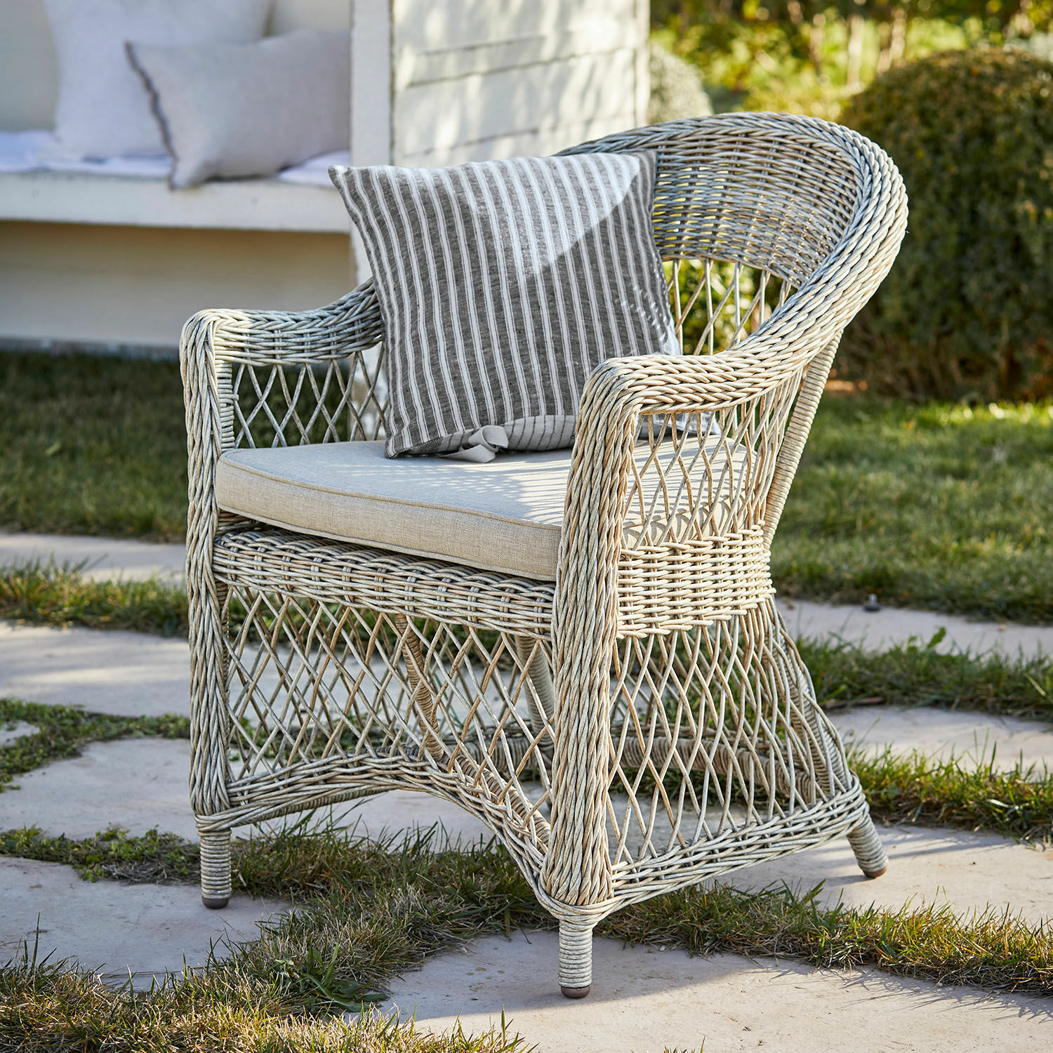 Fotel Lézardrieux Fotel ogrodowy z rattanu w jasnym kolorze z poduszką w paski, idealny do relaksu na zewnątrz
