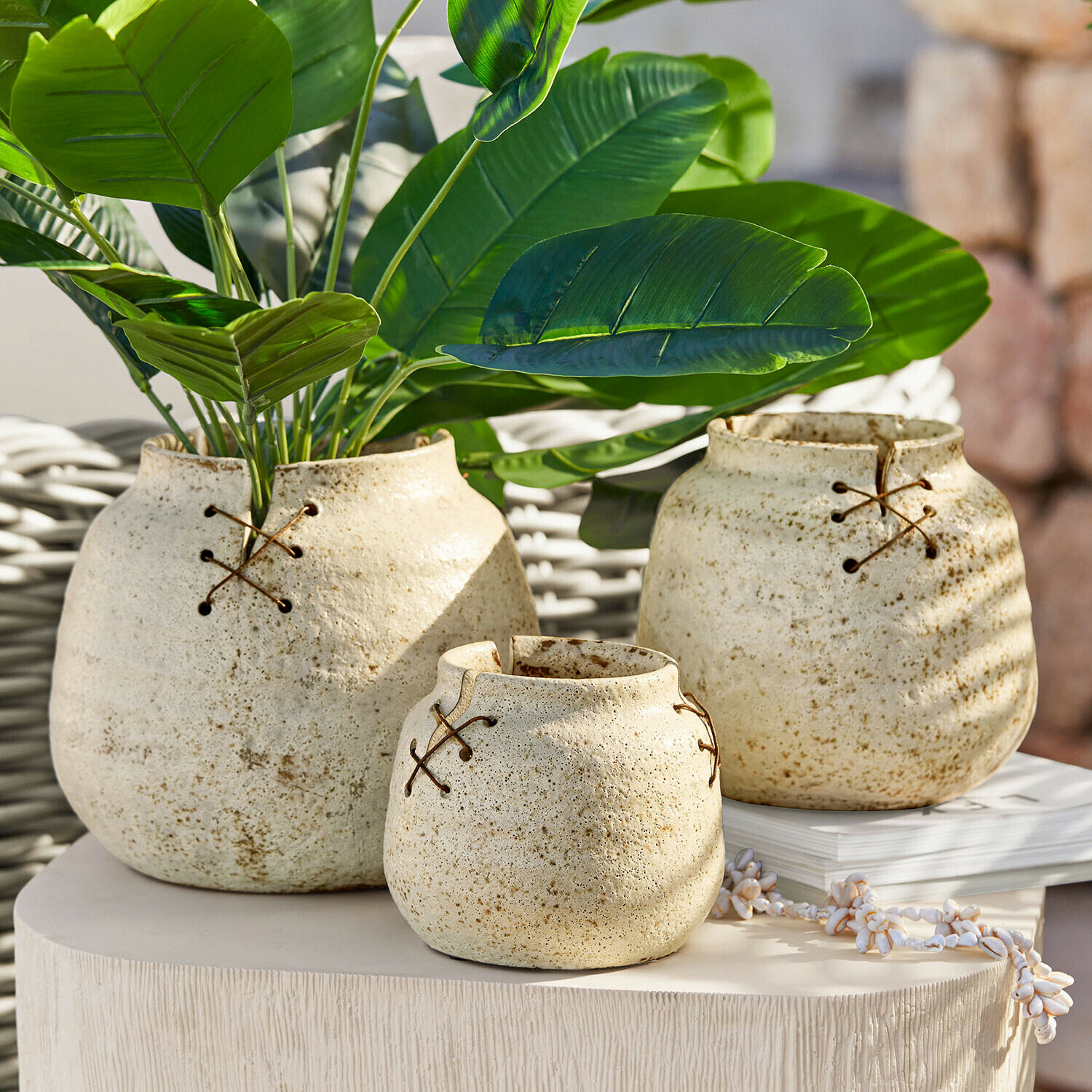 Zestaw trzech ceramicznych wazonów w kremowym kolorze z ozdobnym sznurowaniem, dekoracja wnętrz