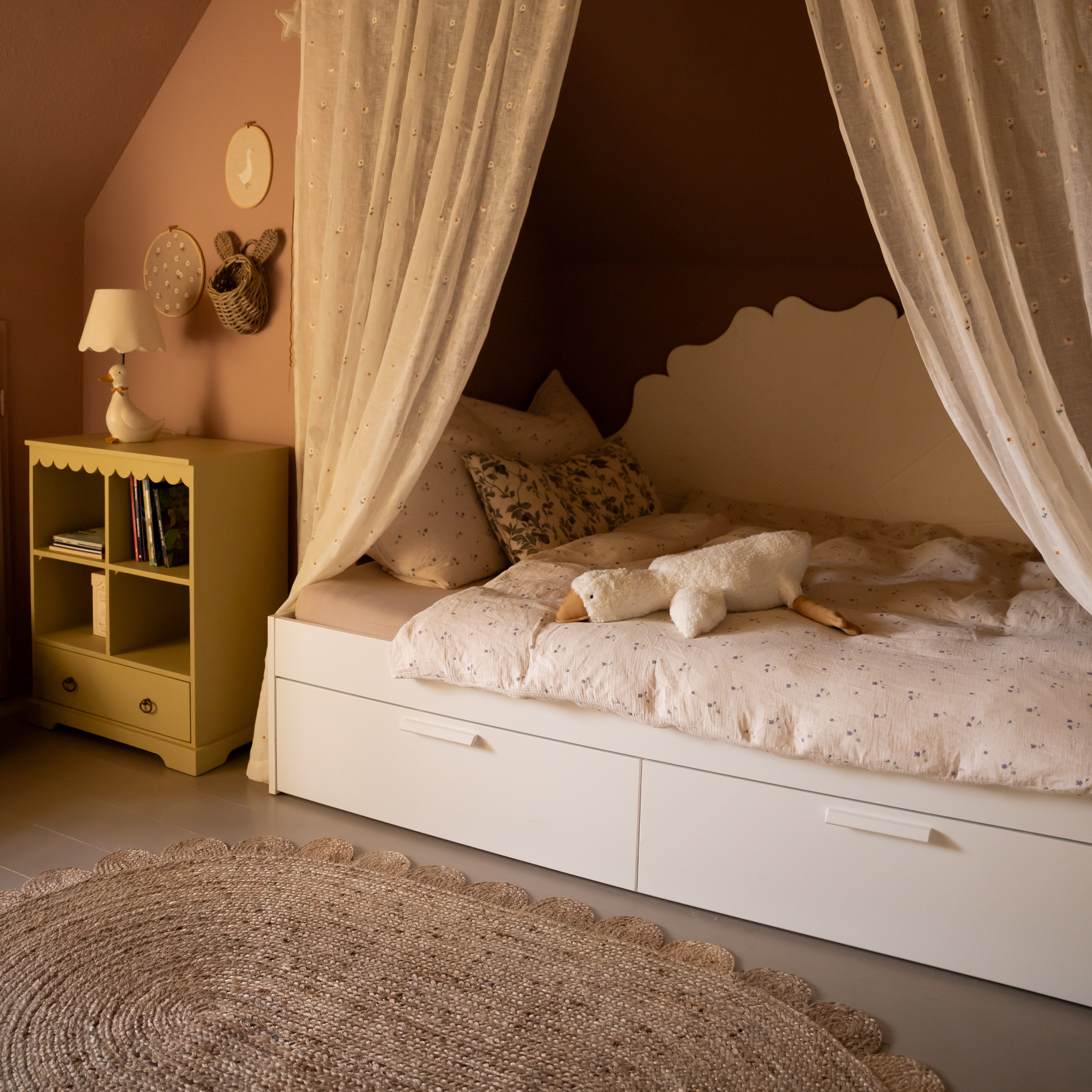 Przytulne łóżko dziecięce z białą ramą i zasłonami, pluszowa zabawka gęsi na pościeli