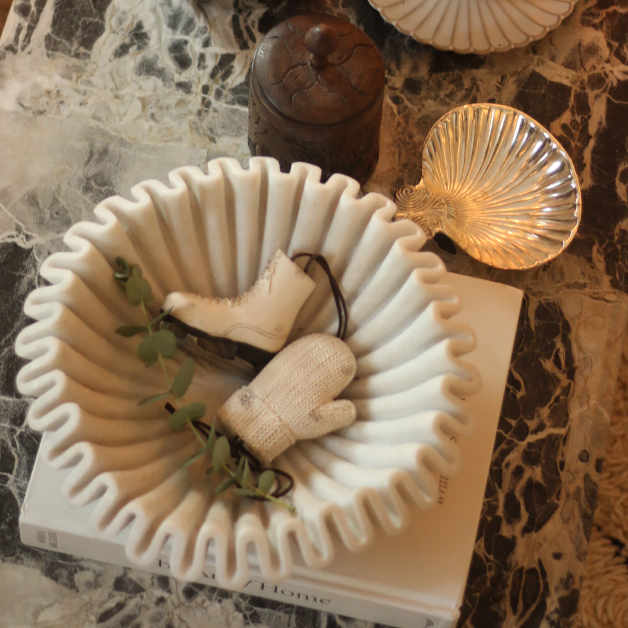Biała ceramiczna miska z falistym brzegiem z ozdobami w kształcie łyżwy i rękawicy na marmurowym stole