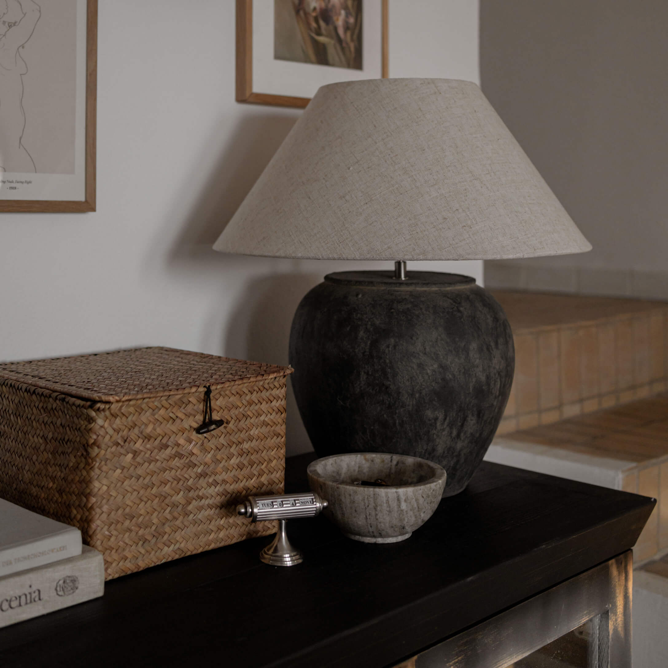 Lampka stołowa z czarną ceramiczną podstawą i beżowym abażurem na ciemnym stole w salonie