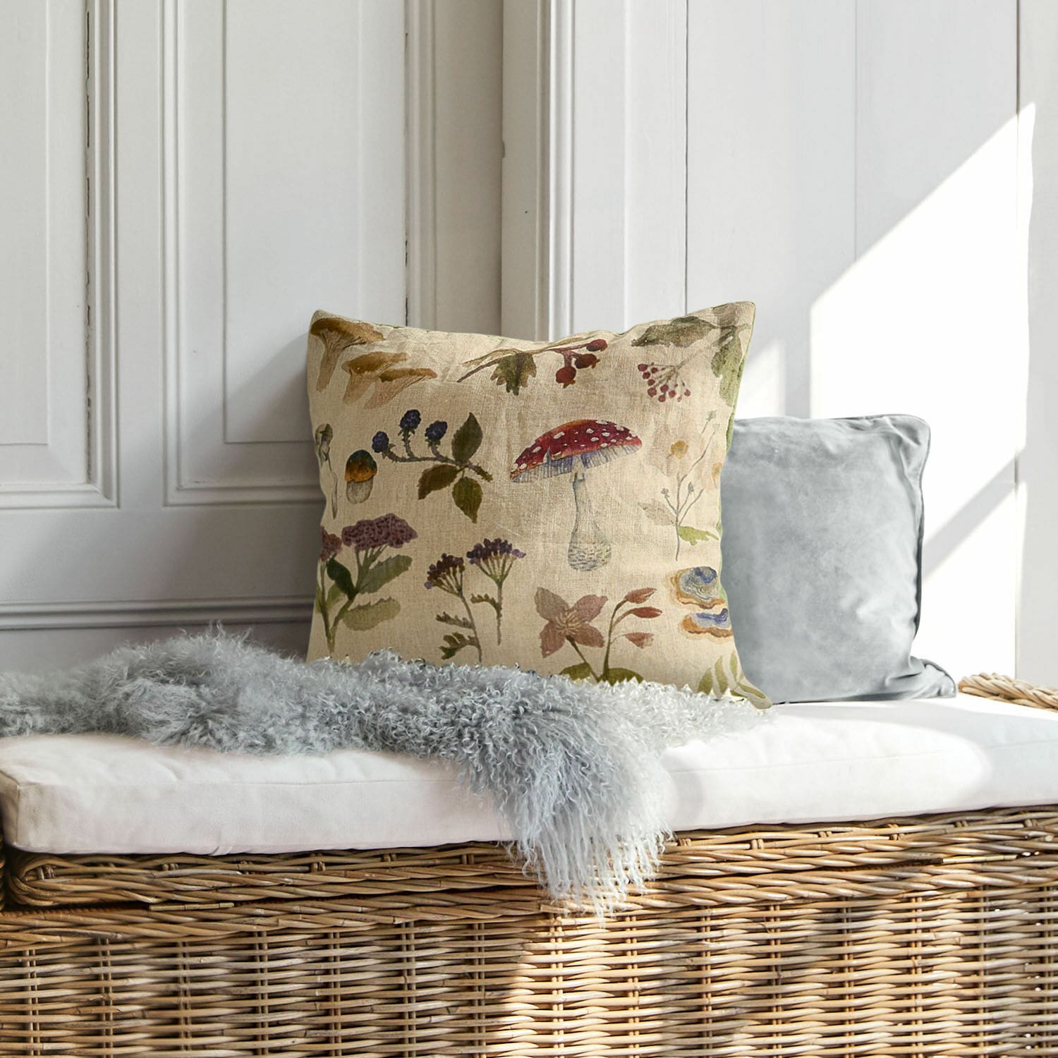 Lniana poduszka dekoracyjna z nadrukiem roślinnym w naturalnych kolorach na wiklinowej ławce