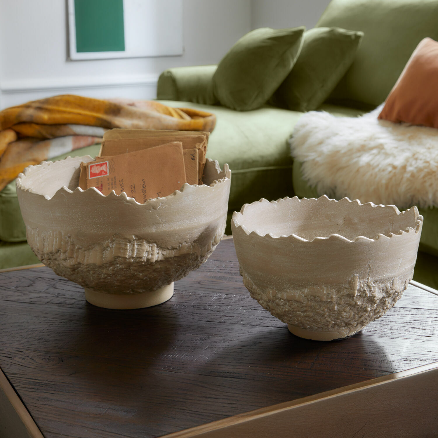 Miska, zestaw 2 szt. Alvendra Dwie beżowe ceramiczne misy z chropowatą fakturą i falistym brzegiem na drewnianym stole