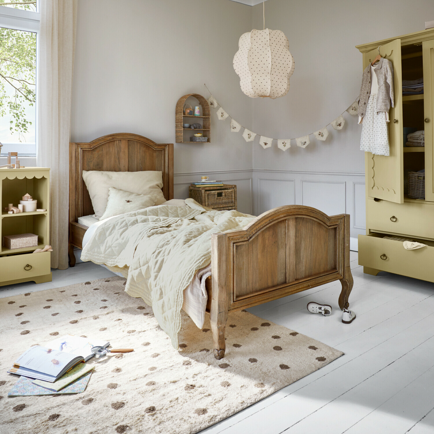 Drewniane łóżko dziecięce z beżową pościelą i kremowym dywanem w jasnym pokoju dziecięcym