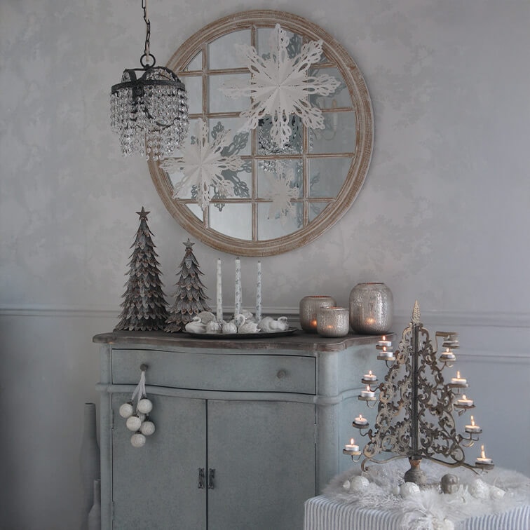 Szara komoda z dekoracjami świątecznymi, metalowe choinki i świecznik z lampionami w stylu vintage
