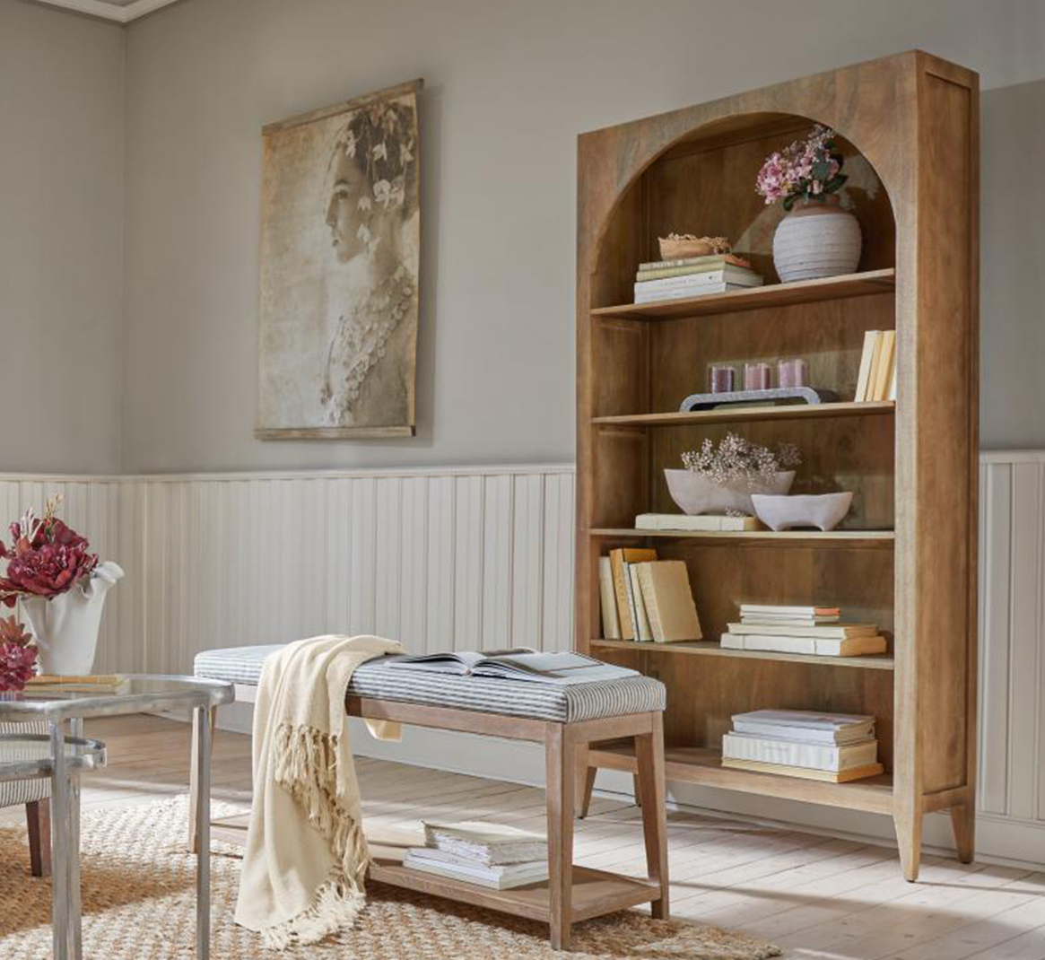 Drewniana półka z łukowym wycięciem, dekoracje i książki w jasnym, naturalnym salonie