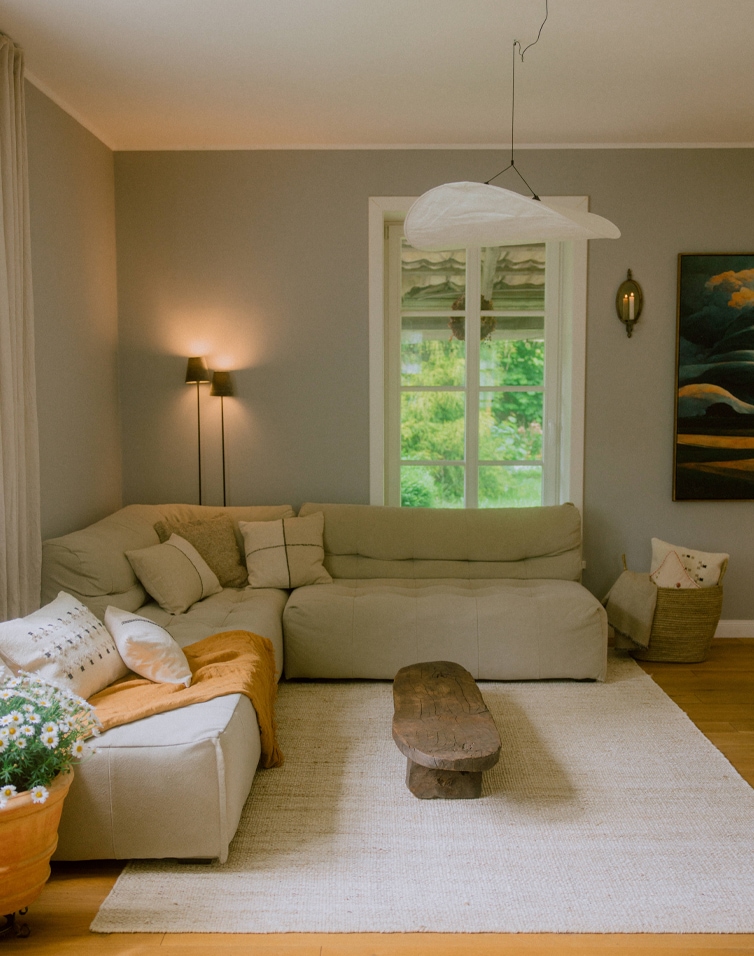 Przytulny salon z beżową sofą narożną, drewnianym stolikiem i naturalnym dywanem, styl skandynawski