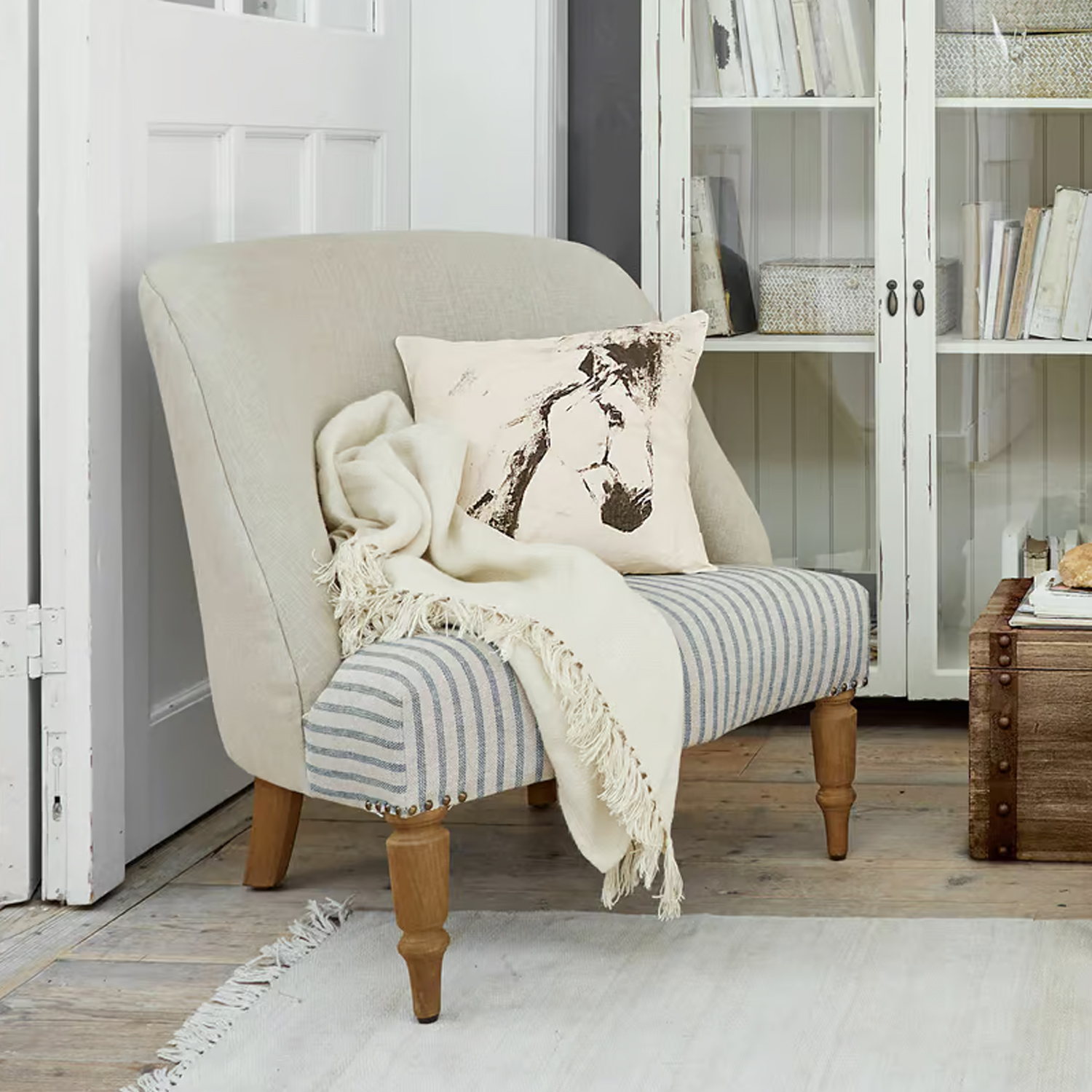 Dwukolorowa tapicerowana sofa z drewnianymi nogami, poduszką z nadrukiem konia i kremowym pledem