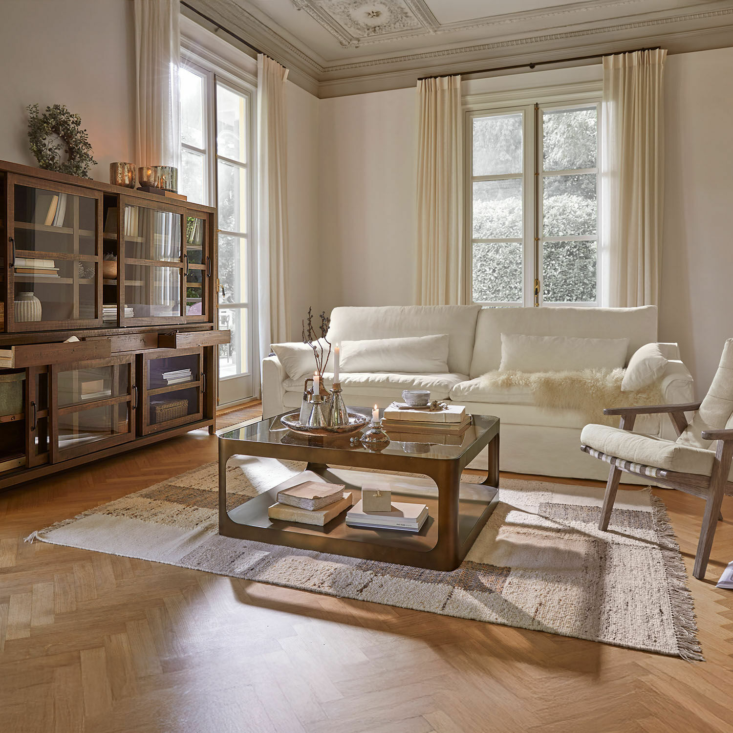 Przytulny salon z białą sofą, drewnianą witryną i metalowym stolikiem kawowym na dywanie