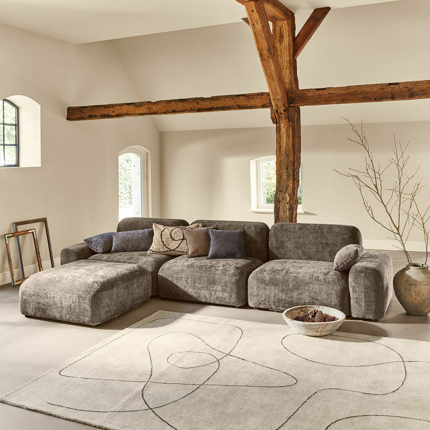 Sofa Marnivelle Szara modułowa sofa z tkaniny w nowoczesnym salonie z drewnianymi belkami i jasnym dywanem