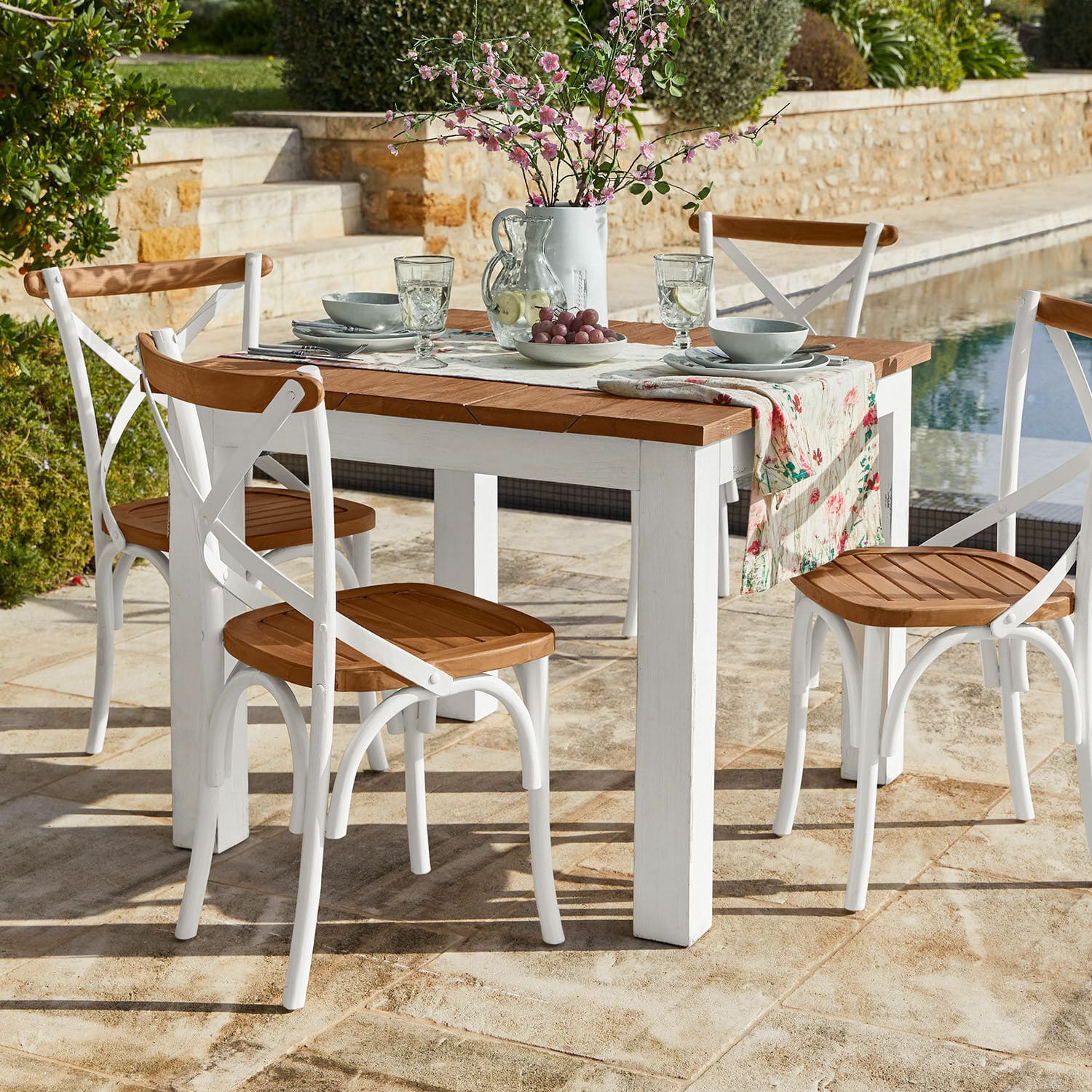 Stół Kirkdale Zestaw mebli ogrodowych z białym drewnianym stołem i krzesłami z drewnianymi siedziskami na tarasie