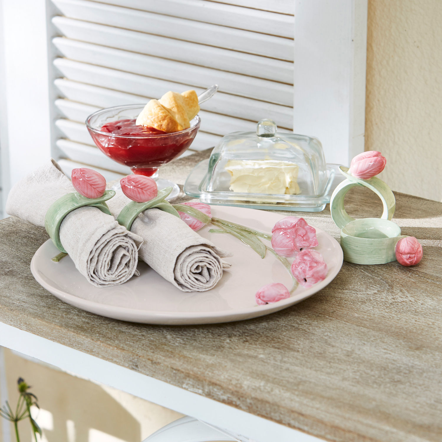 Obrączka na serwetki, zestaw 4 szt. Monique Ceramiczne pierścienie na serwetki z różowymi kwiatami na beżowym talerzu na drewnianym stole