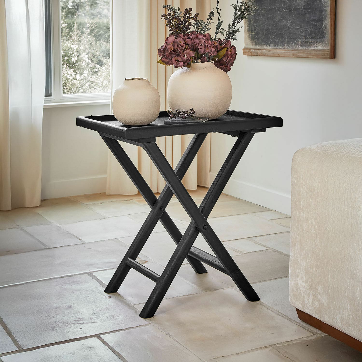 Czarny składany stolik z drewna z dwoma beżowymi wazonami i dekoracją kwiatową w salonie