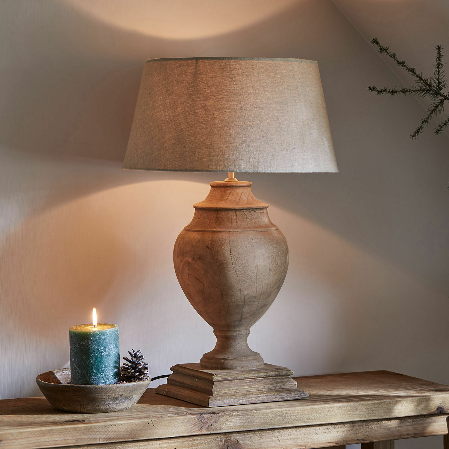 Lampa stołowa Sauverny Lampka stołowa z drewnianą podstawą i beżowym abażurem na drewnianym stole, dekoracyjna świeca obok