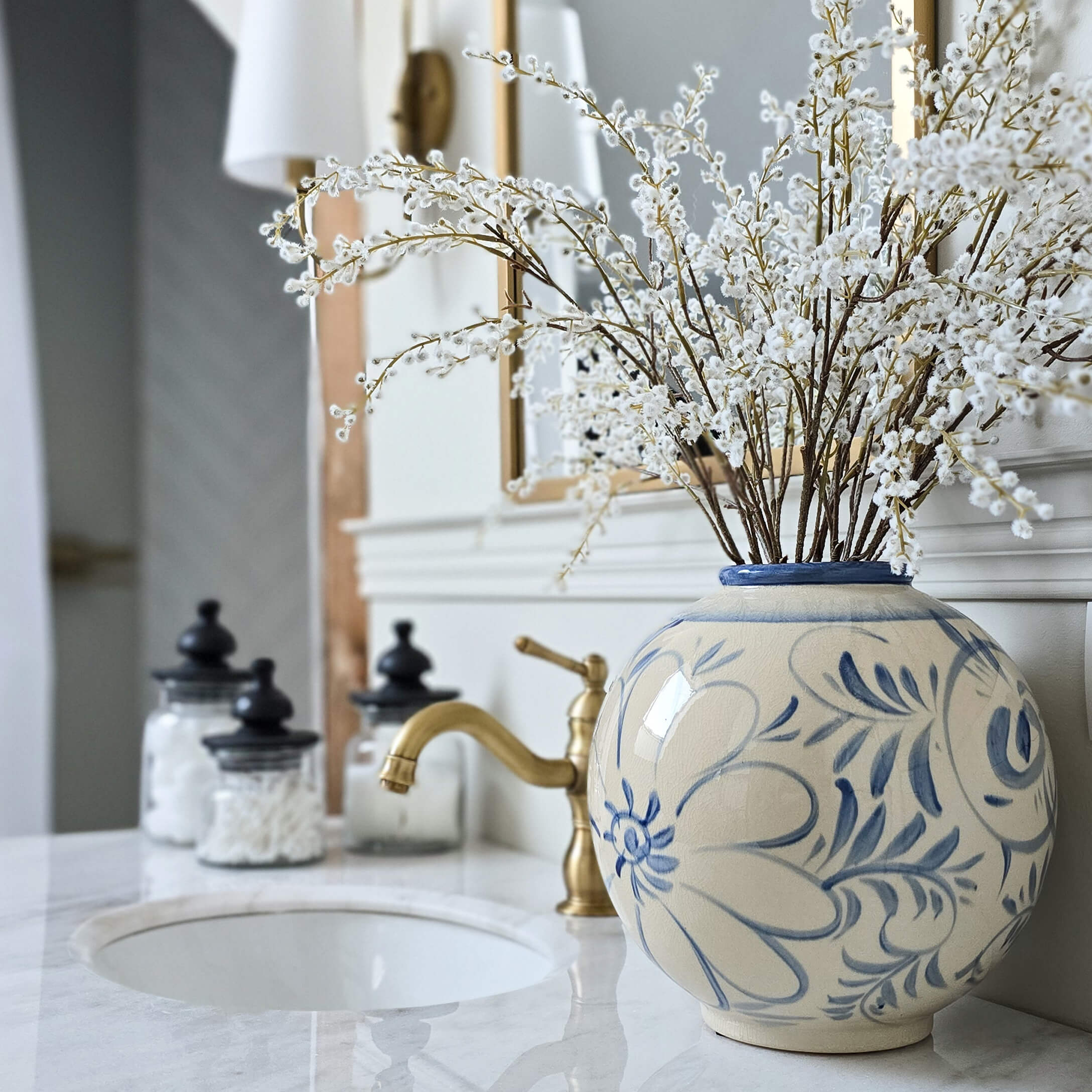 Ceramiczna okrągła waza z niebieskim kwiatowym wzorem na marmurowej łazienkowej półce z dekoracją