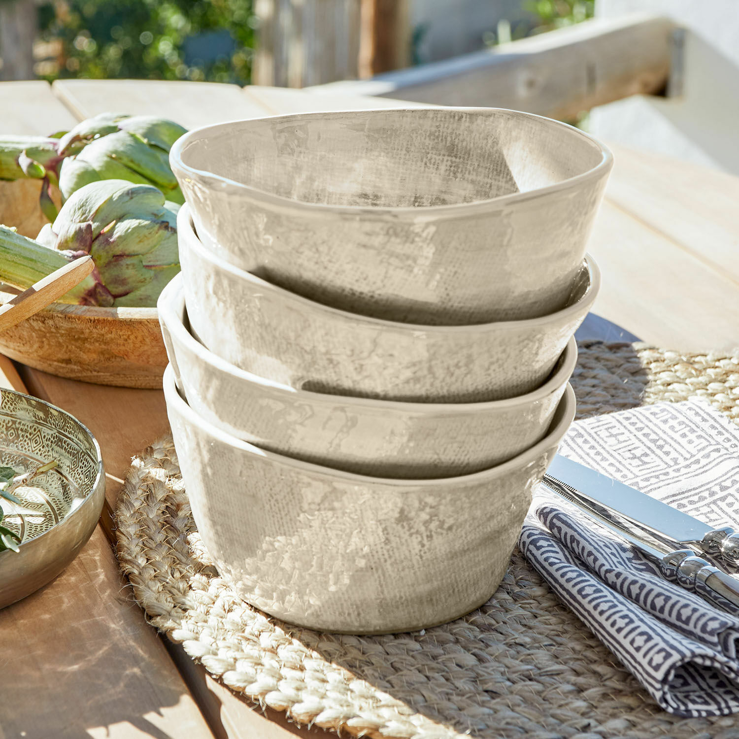 Zestaw 4 miseczek Luganville Zestaw czterech ceramicznych misek w kremowym kolorze na naturalnym podkładzie z juty