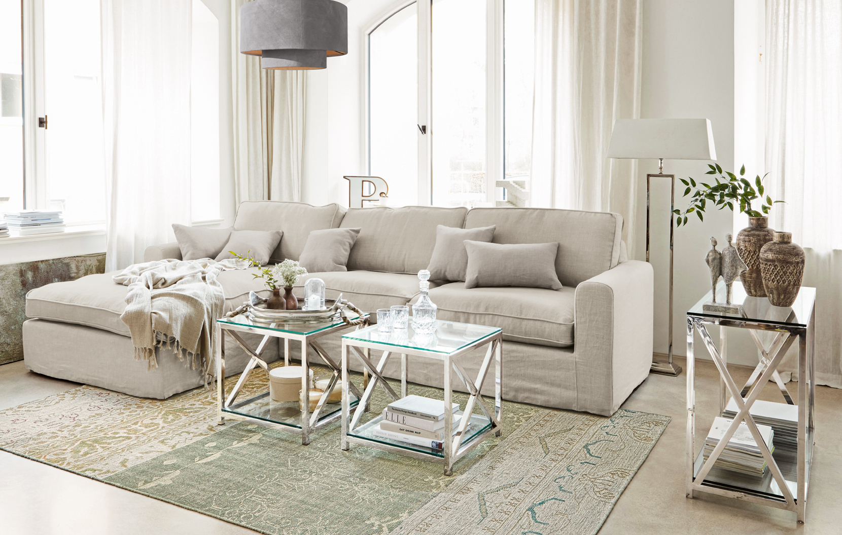 Beżowa klasyczna sofa z lnu z poduszkami i szklanymi stolikami na metalowych ramach w salonie