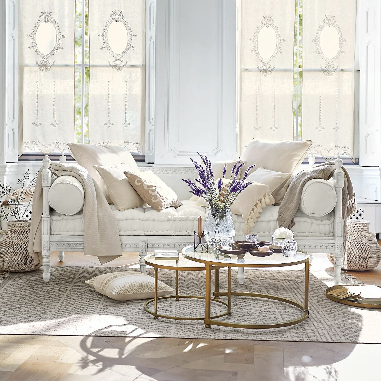 Sofa Douville Biała drewniana sofa z kremowymi poduszkami i złotym stolikiem kawowym w jasnym salonie