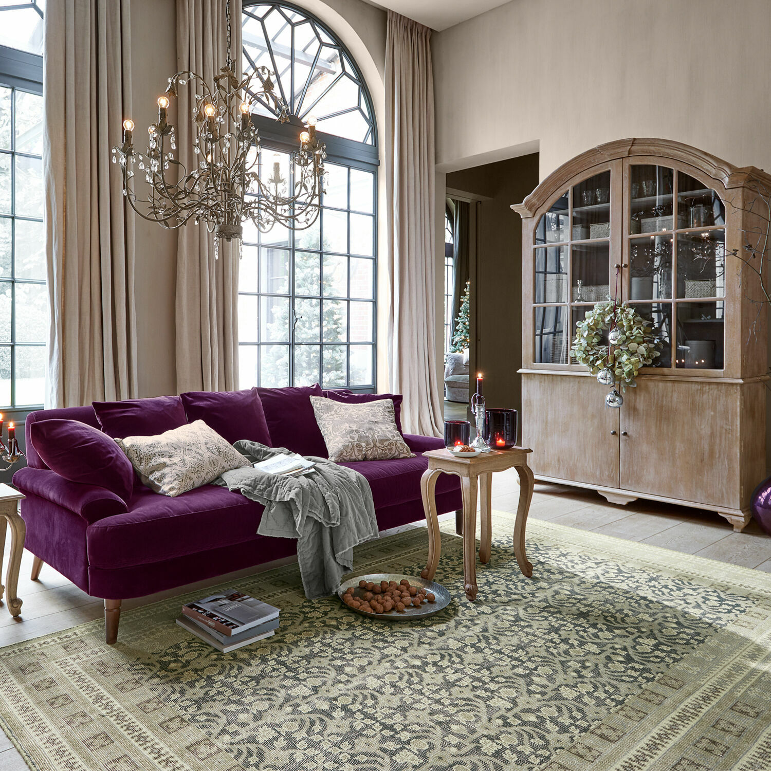 Fioletowa welurowa sofa w salonie z drewnianą witryną i ozdobnym dywanem w stylu vintage