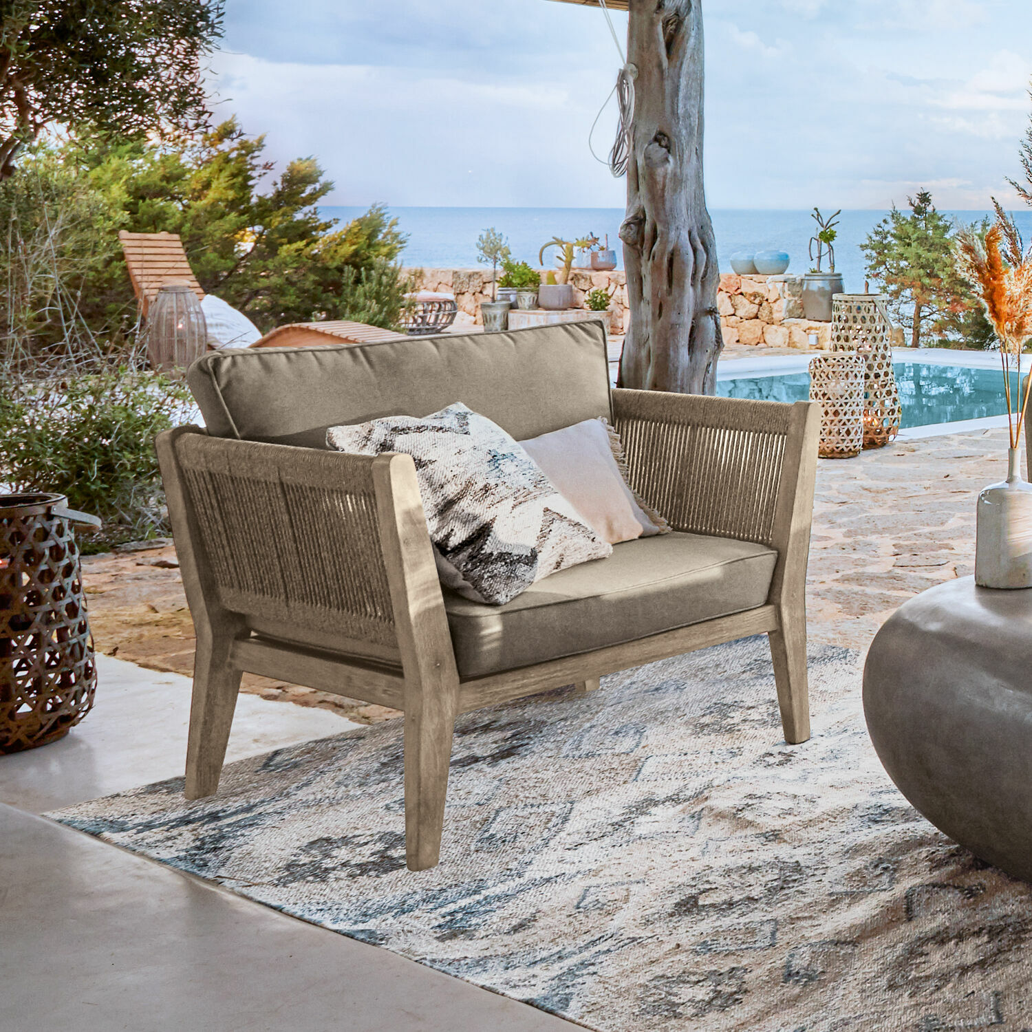 Fotel 100% FSC® Biarritz Sofa ogrodowe z drewna i tkaniny w kolorze beżowym na tarasie z widokiem na morze
