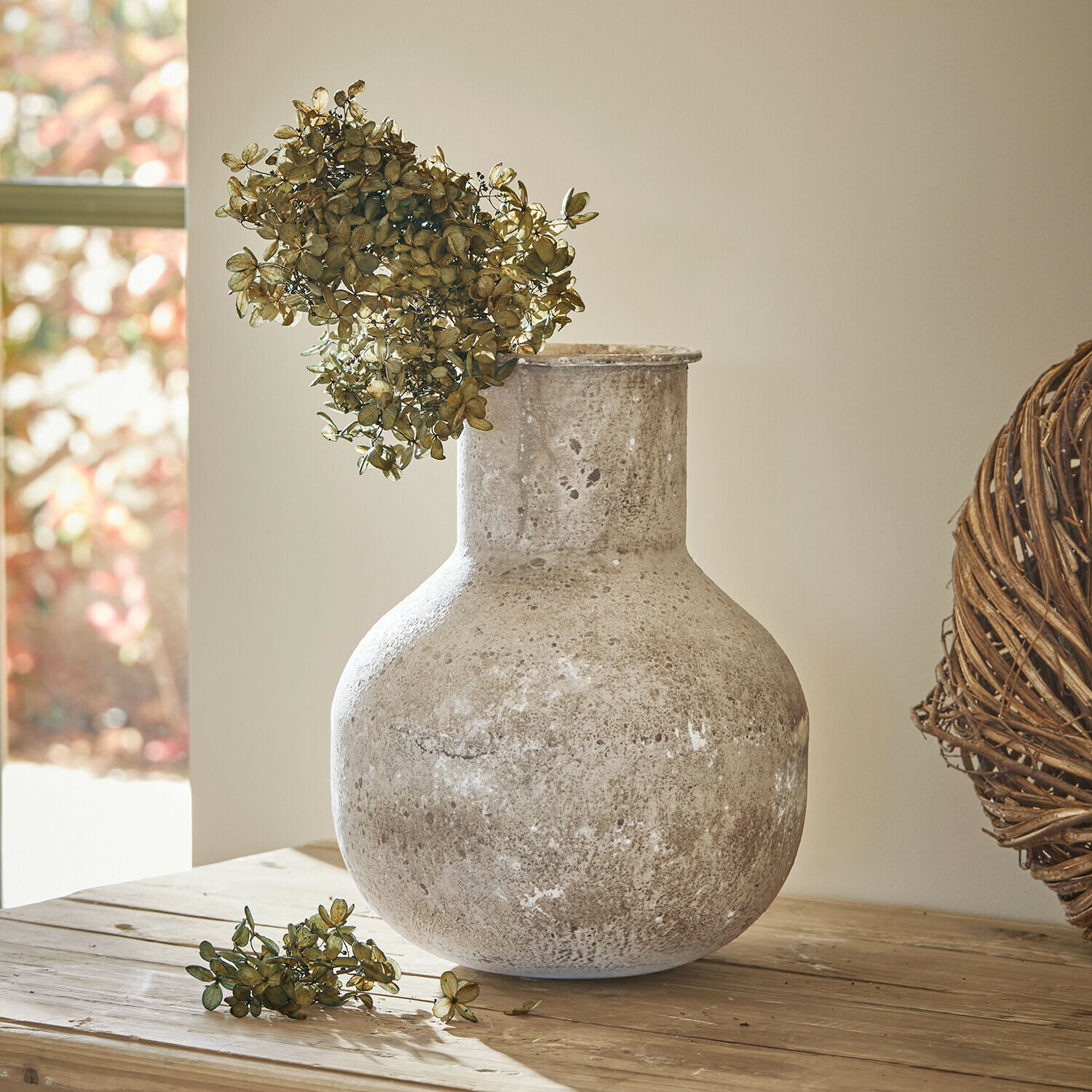 Wazon Delavine Duży ceramiczny wazon w kolorze szarym z suszonymi kwiatami na drewnianym stole w jasnym wnętrzu