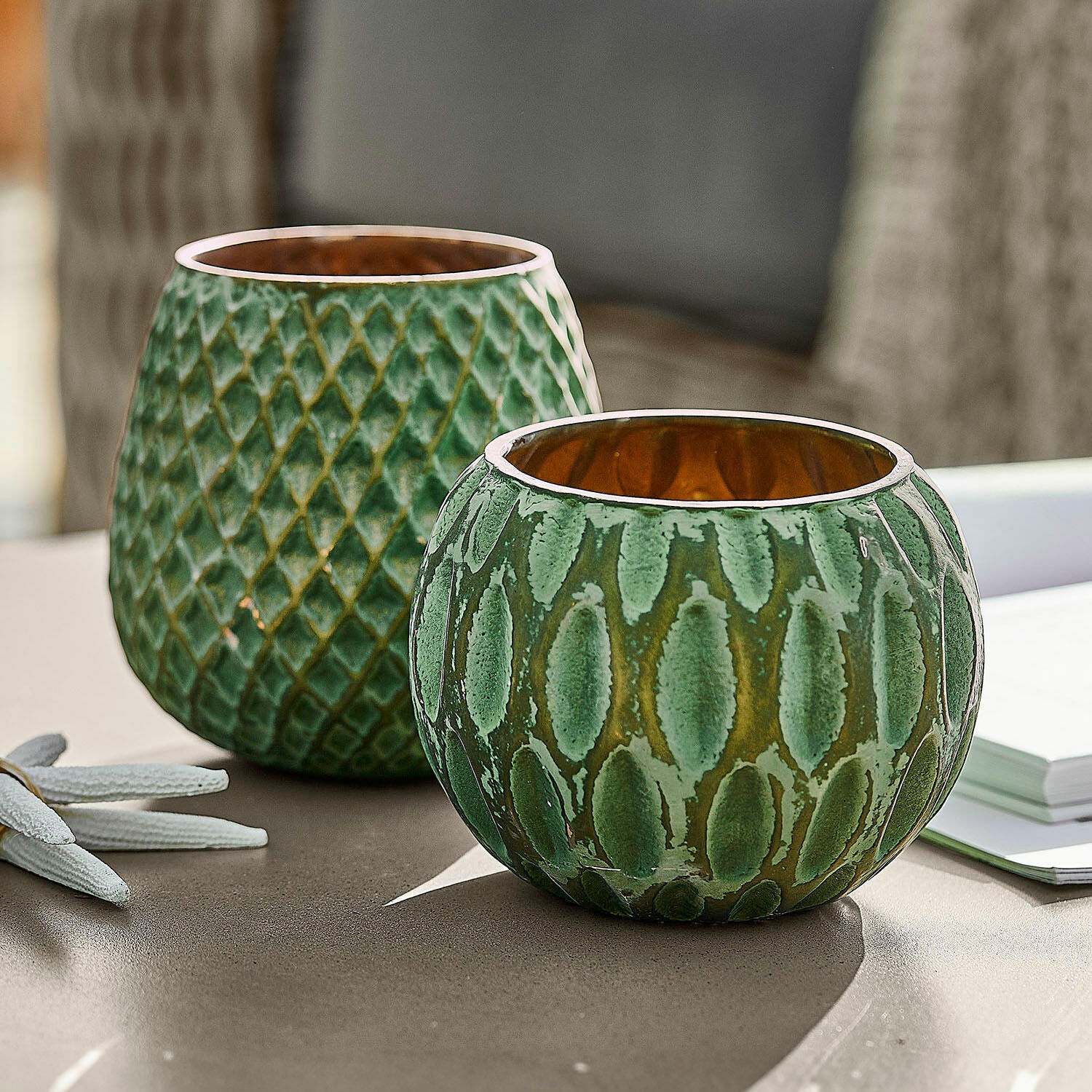 Zestaw 2 lampionów Xerice Zestaw dwóch zielonych ceramicznych świeczników z fakturą i złotym wnętrzem na stole
