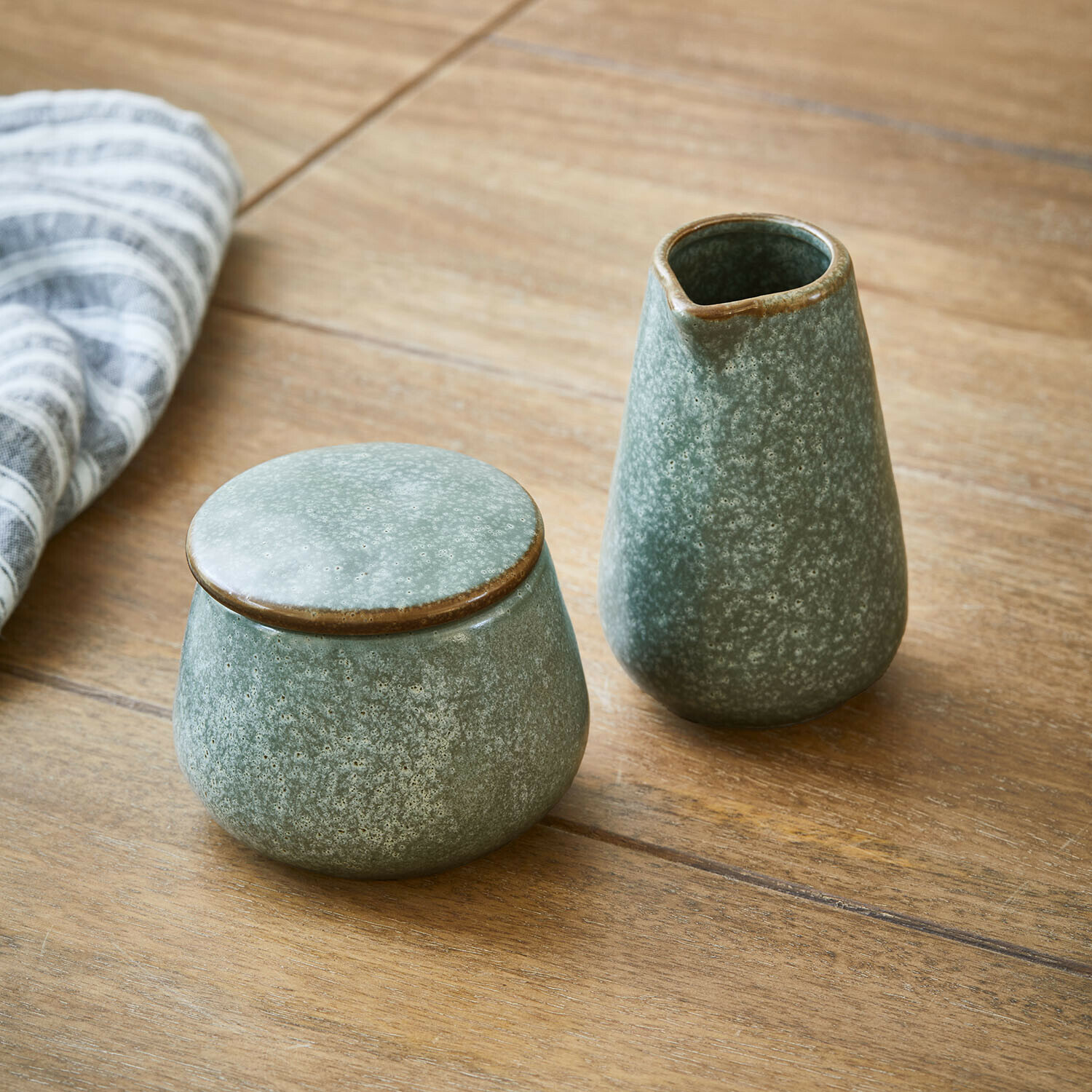 Cukiernica i mlecznik Biarré Zestaw ceramicznych naczyń w zielonym kolorze z pokrywką i dzbankiem na drewnianym stole