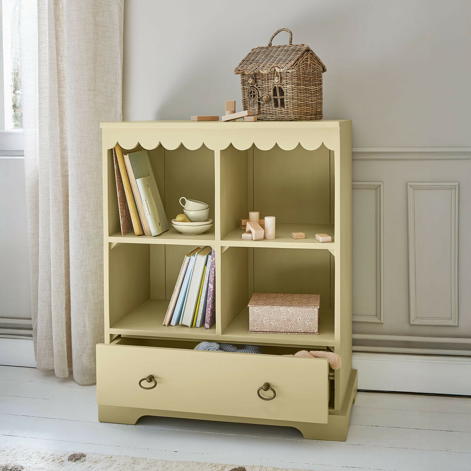 Beżowa drewniana komoda z czterema półkami i szufladą, dekoracyjny kosz z wikliny na górze