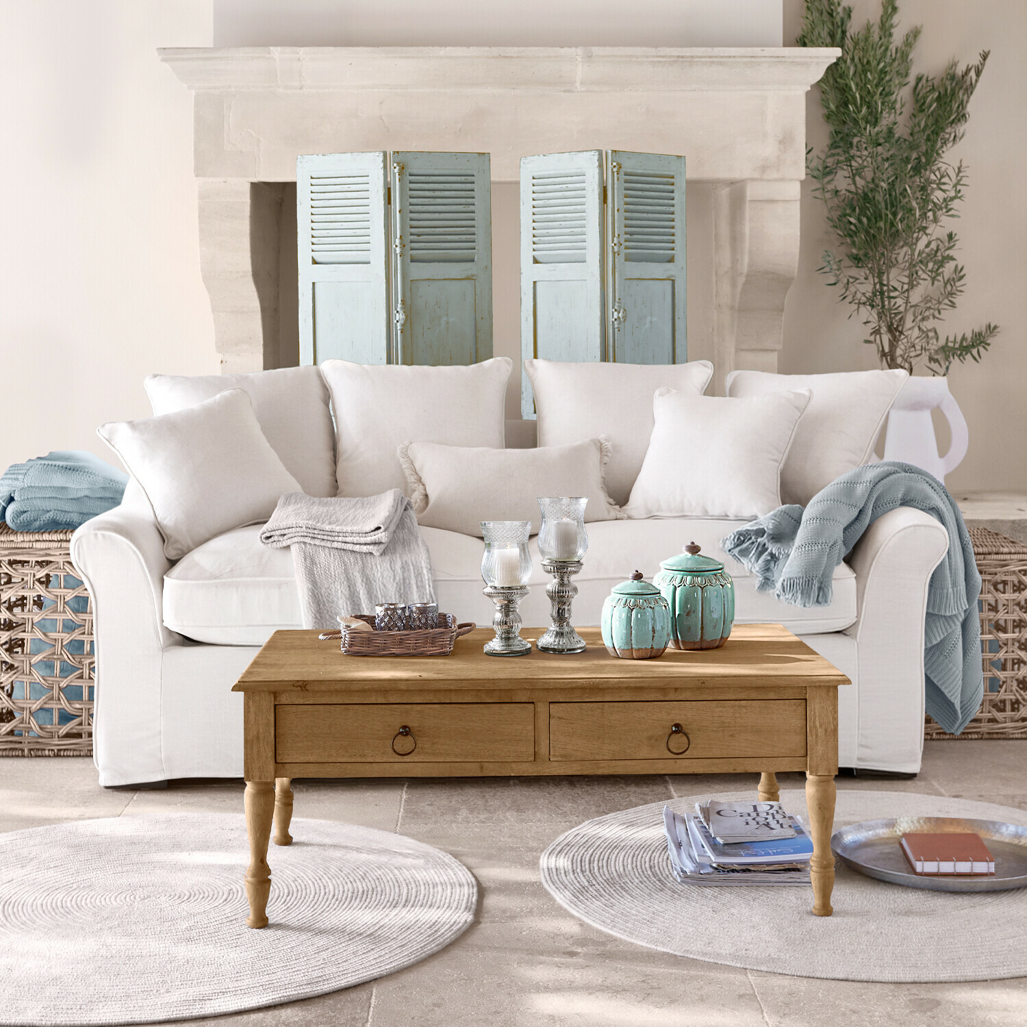 Sofa Long Beach Beżowa sofa z poduszkami i drewniany stolik kawowy z dekoracjami w jasnym salonie z kominkiem