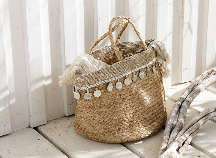 Boho kosz z plecionego naturalnego materiału z ozdobnymi monetami i jasnym szalem, dekoracja wnętrz.