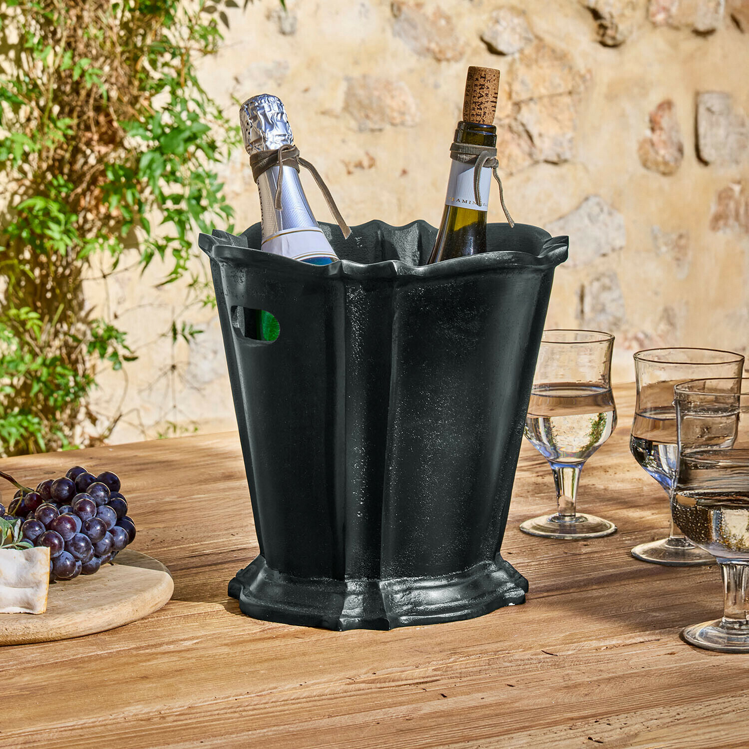 Chłodziarka do napojów Trévaux Czarny metalowy kubełek na lód z dwoma butelkami wina na drewnianym stole na zewnątrz