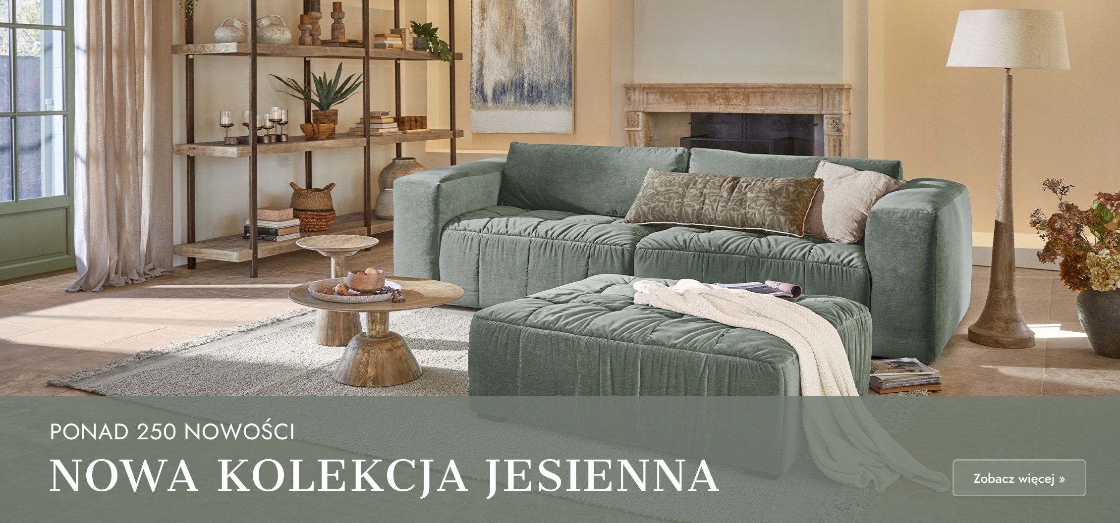 Zielona aksamitna sofa z poduszkami i pufą w przytulnym salonie z drewnianymi stolikami i kominkiem