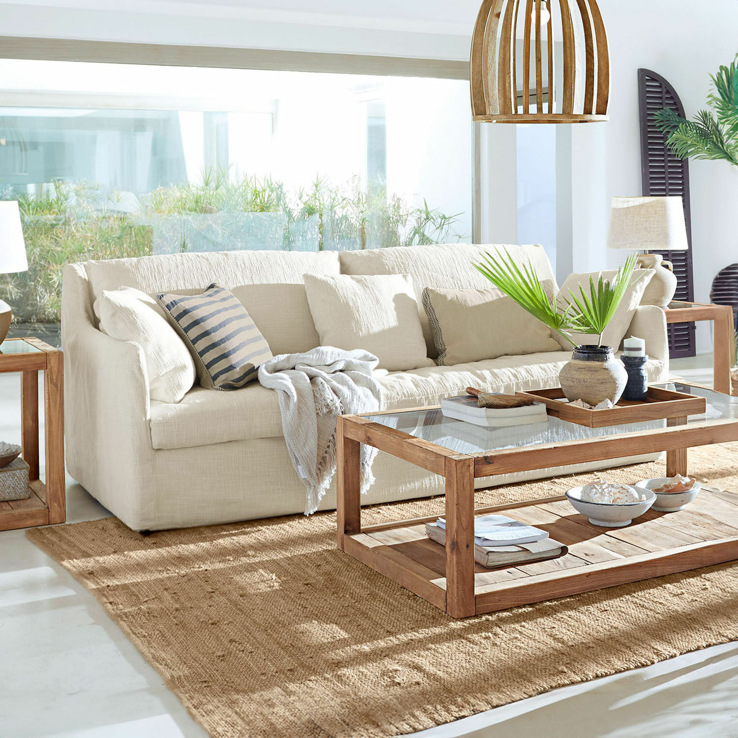 Sofa Shadowfield Beżowa sofa z tkaniny w jasnym salonie z drewnianym stolikiem kawowym i naturalnym dywanem