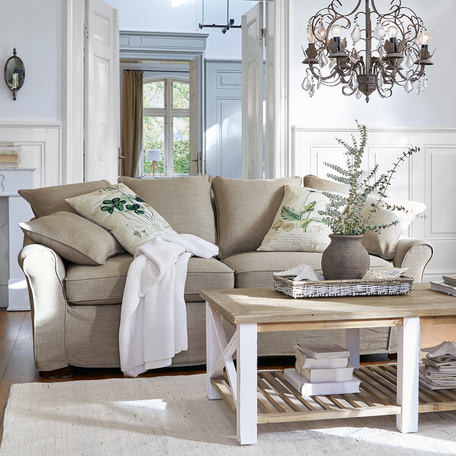 Sofa Long Beach Beżowa sofa z tkaniny z poduszkami dekoracyjnymi i drewnianym stolikiem kawowym w jasnym salonie