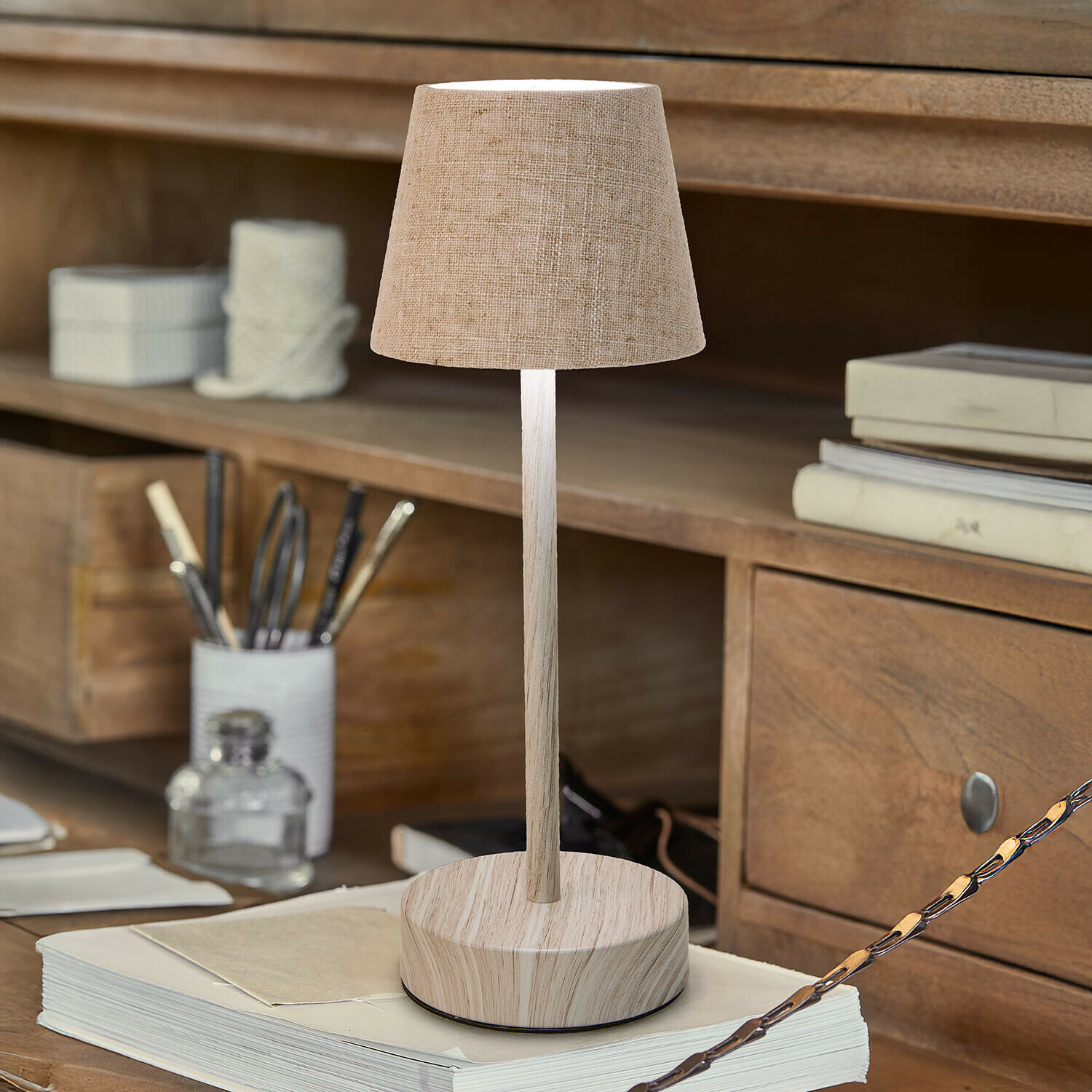 Lampa stołowa z możliwością ładowania Sylvainie Lampka stołowa z beżowym abażurem i drewnianą podstawą na biurku z książkami i przyborami do pisania