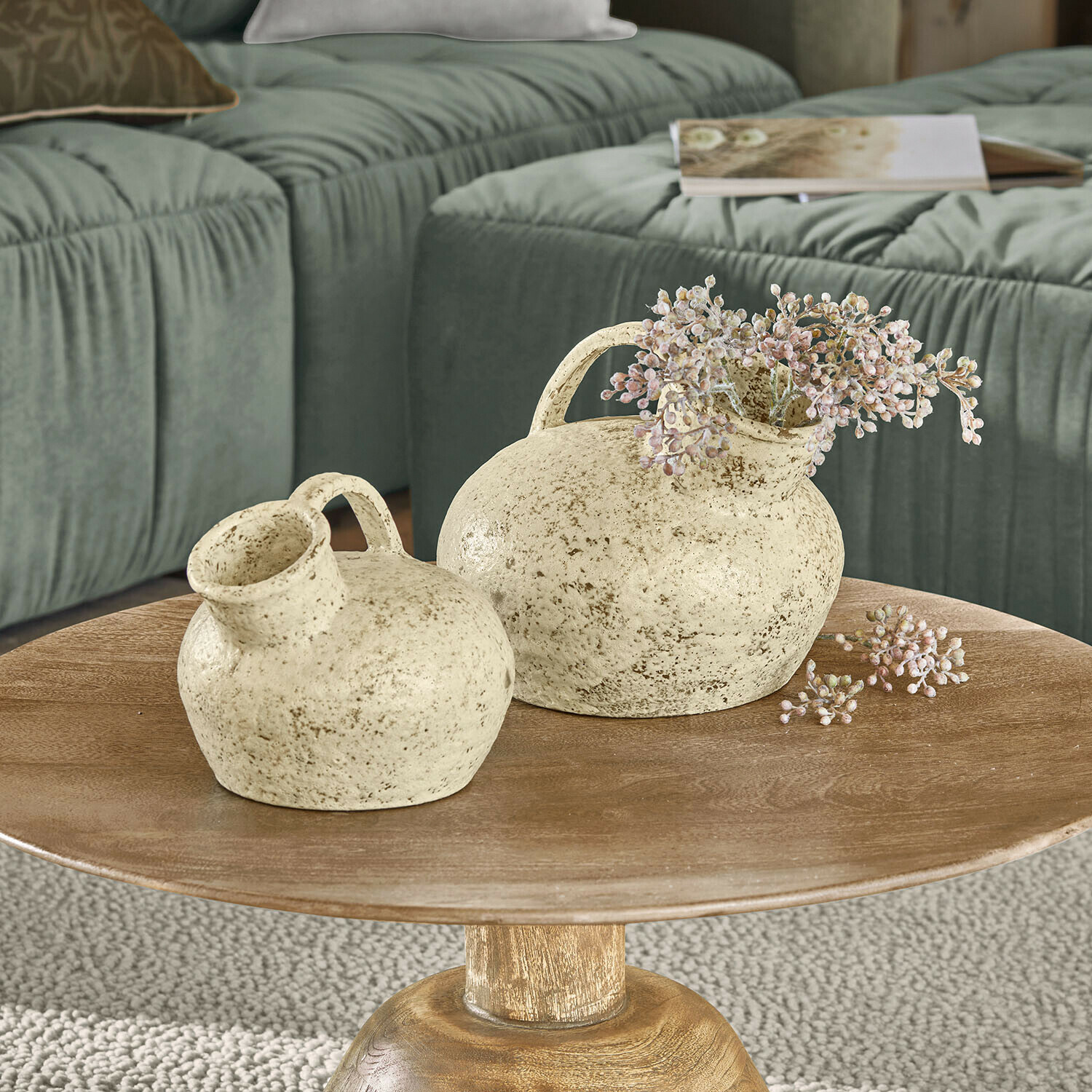 Vase 2er Set Gravière Dwie kremowe ceramiczne wazony z uchwytami na drewnianym stoliku w salonie z zieloną sofą