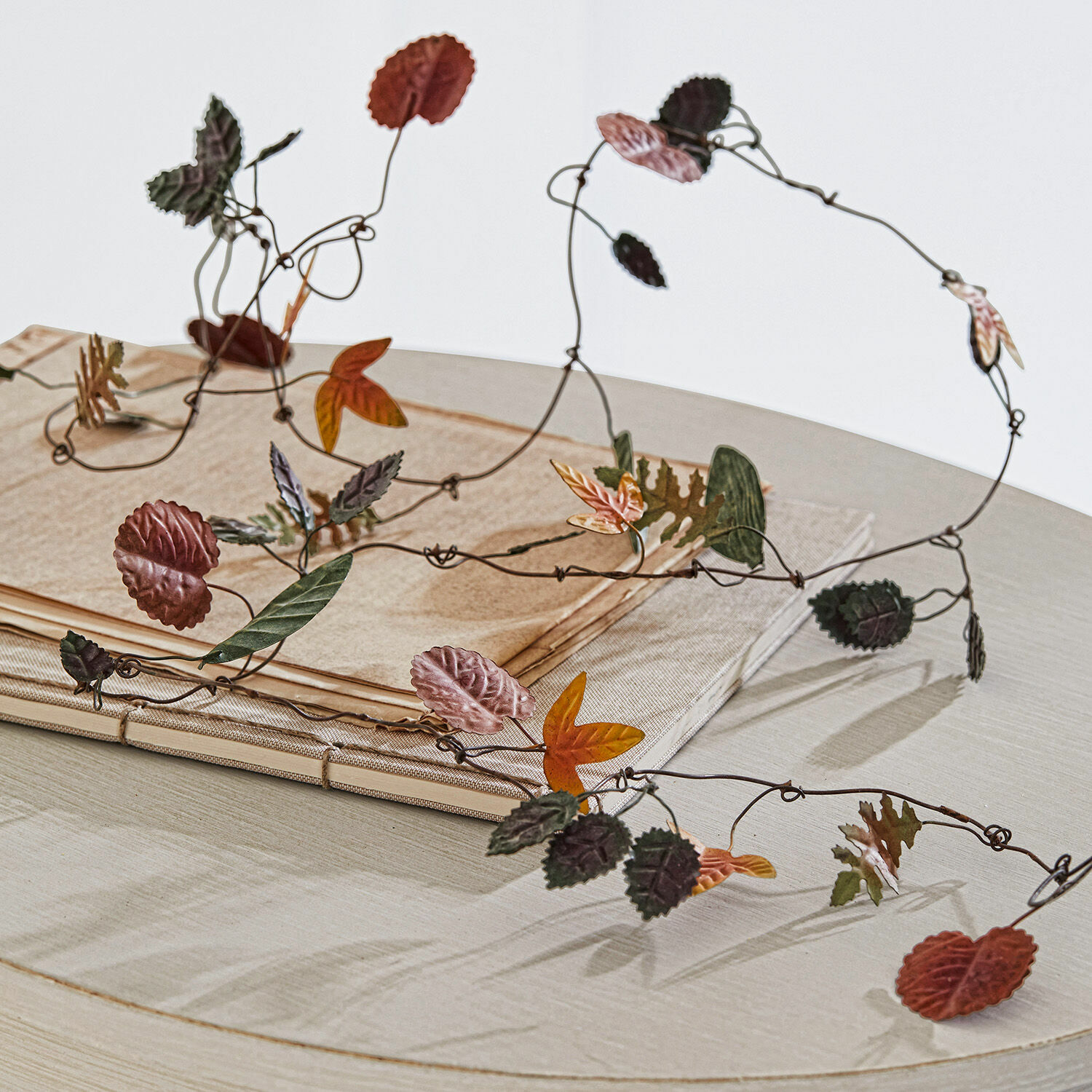 Dekoracyjny łańcuch z metalowymi liśćmi w jesiennych kolorach na jasnym stole